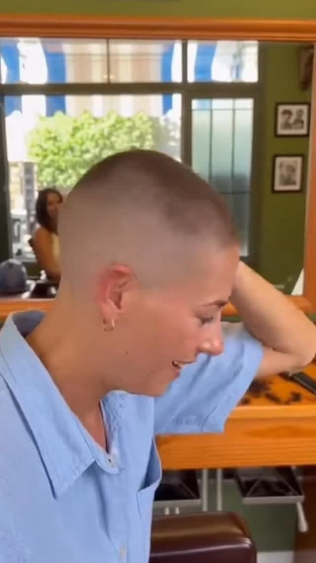 Person with a closely cropped buzz cut seated in a bright room