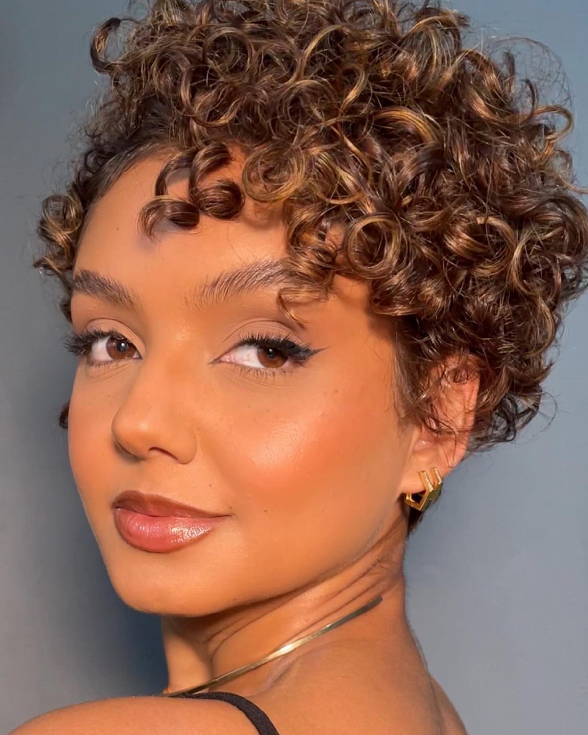 Woman showcasing a short curly pixie bob with defined brown ringlets