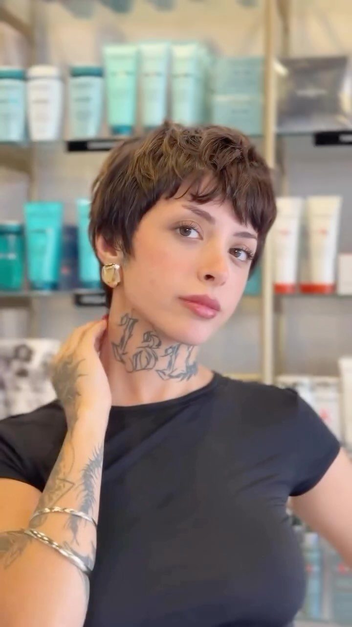 Woman showing a tousled brown pixie cut with soft bangs and sideburns
