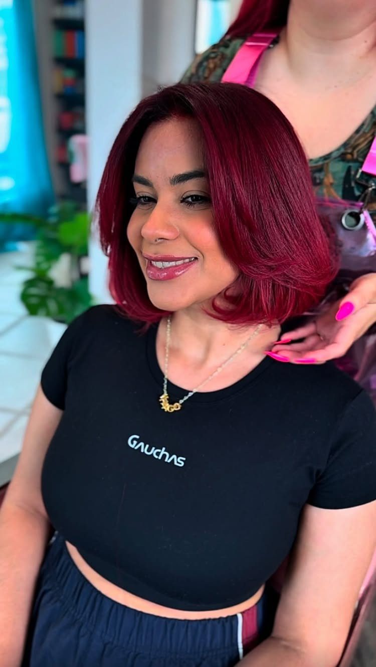 Woman with a burgundy jaw-length bob curled inward at a salon