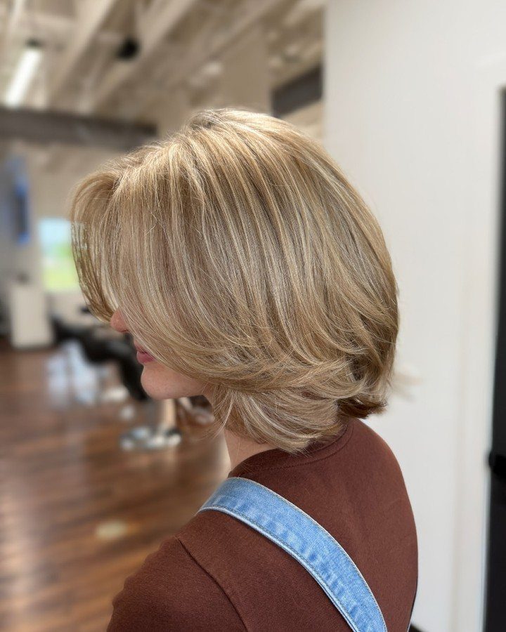 Blonde asymmetrical layered bob with longer face-framing pieces and a shorter back