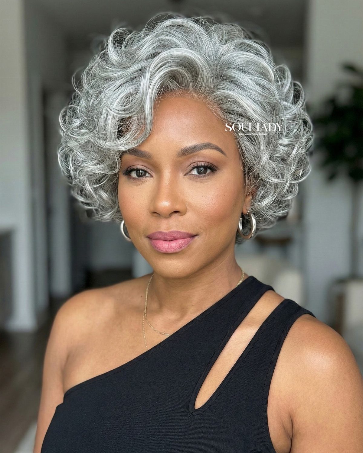 Woman with short, voluminous silver-gray waves and a black sleeveless top