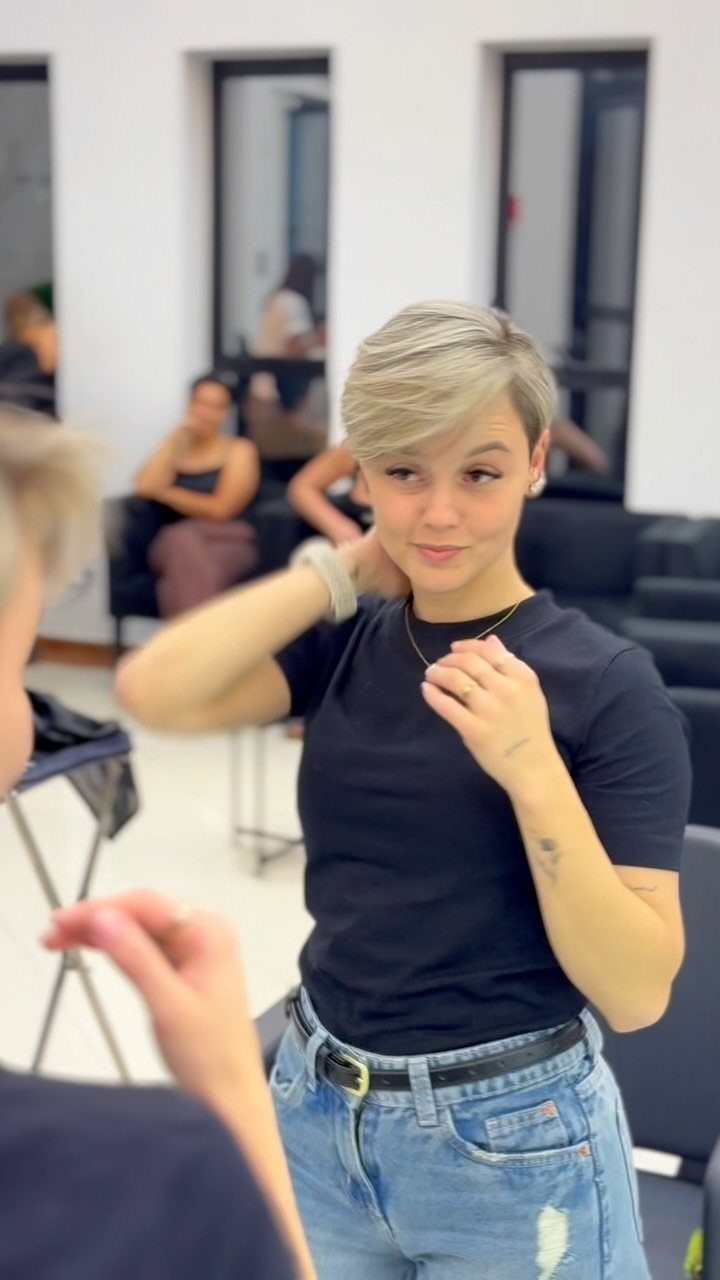 Blonde short pixie haircut with pronounced side-swept bangs in a salon