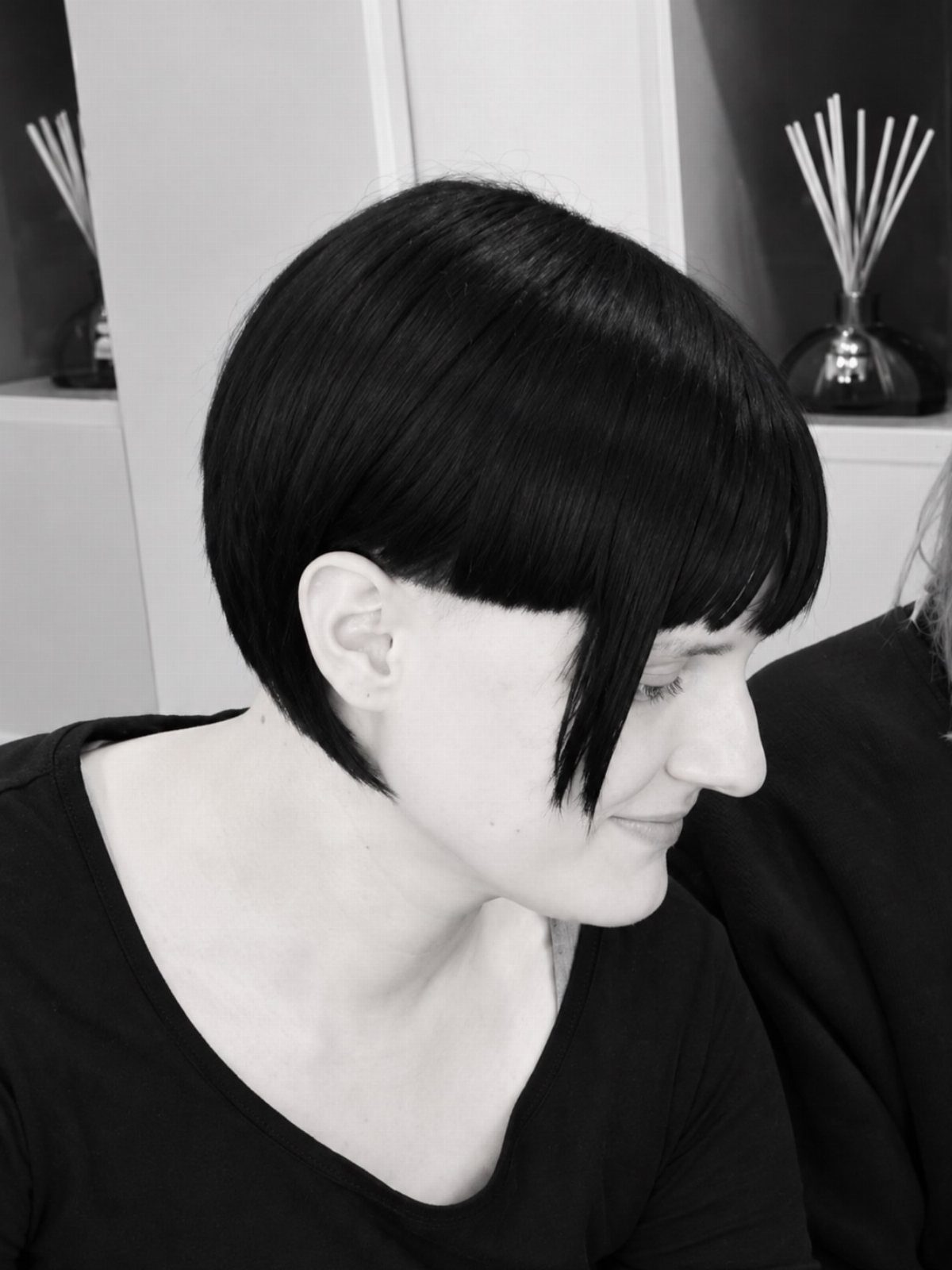 Rounded black bob with straight bangs shown in a side-profile portrait