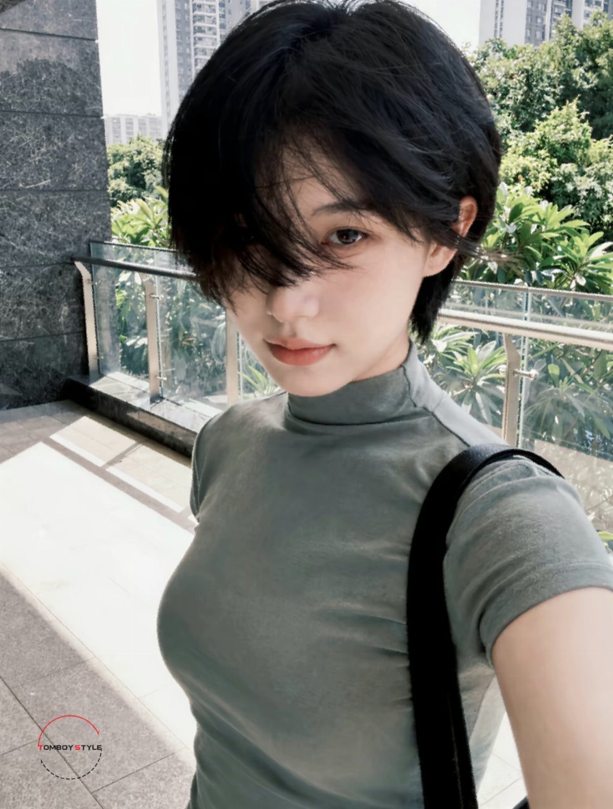 Person with tousled short black hair and long side-swept bangs outdoors