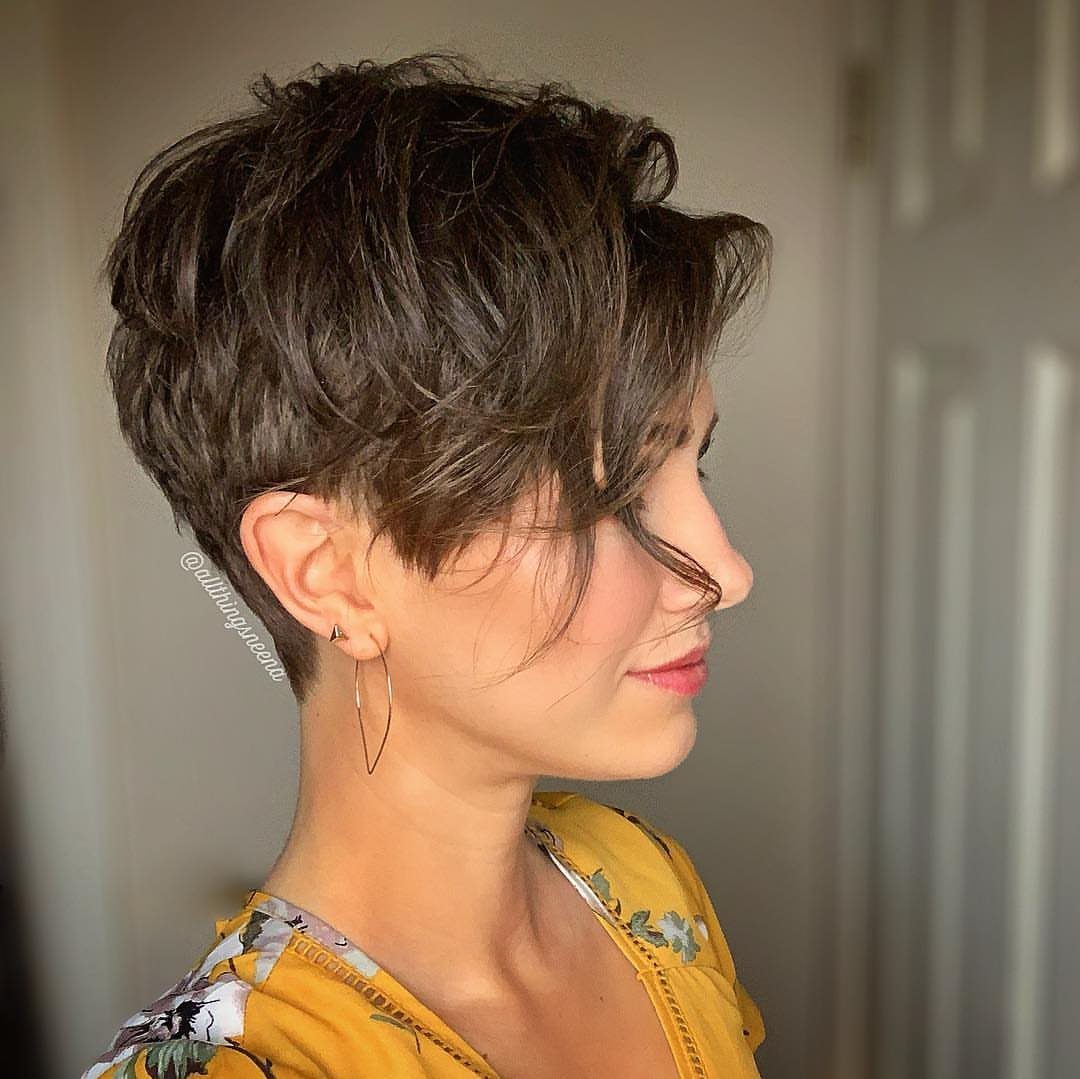 Woman with tousled dark pixie hair swept forward over her forehead