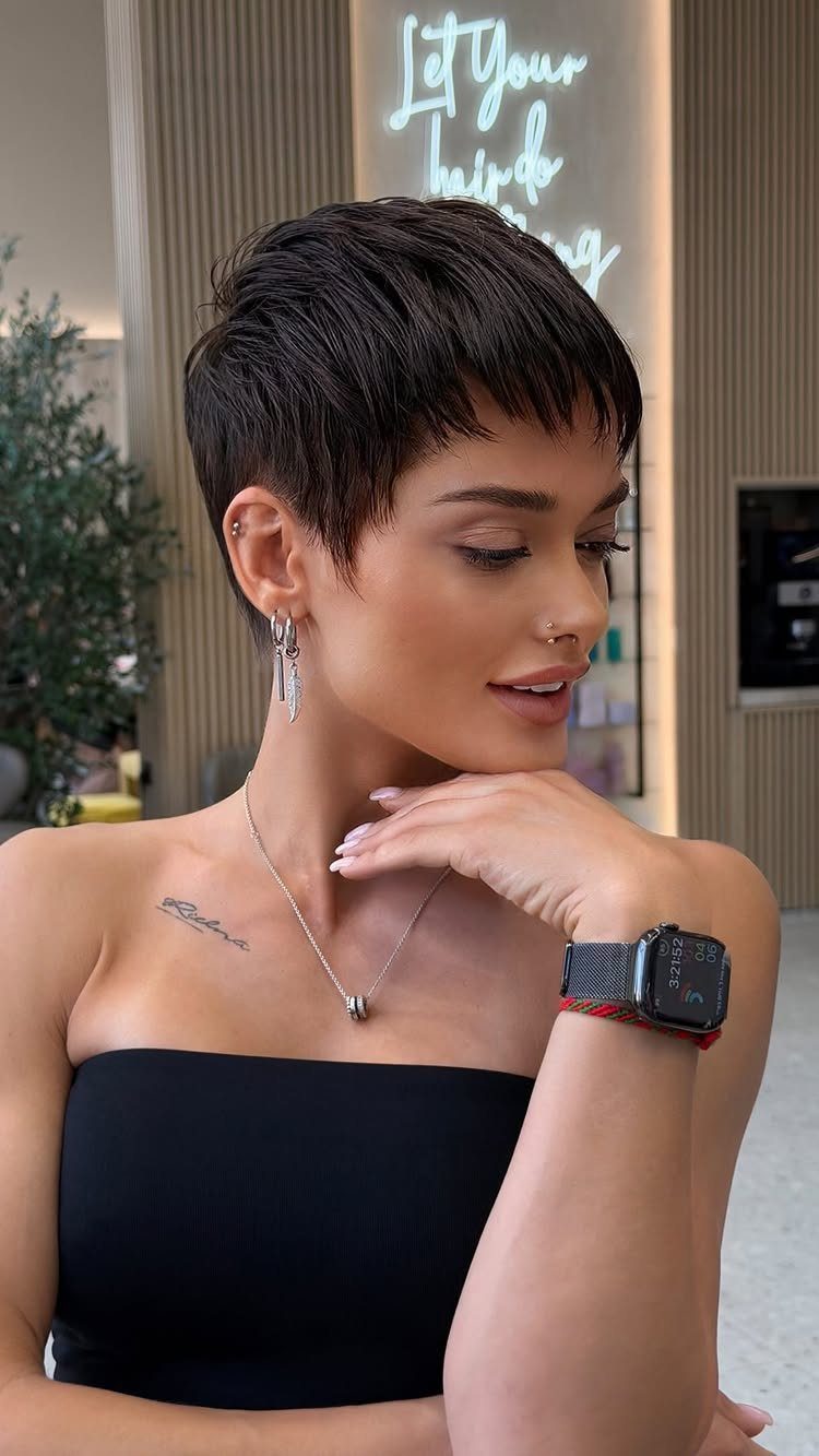 Woman posing with a short dark pixie cut and side-swept fringe