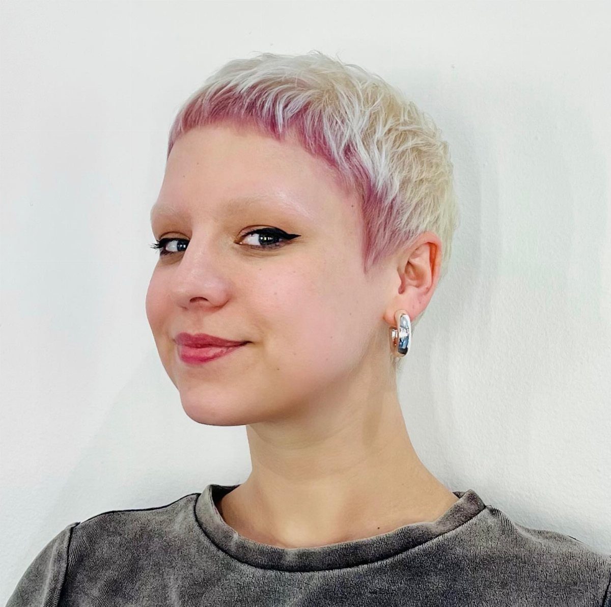 Short tapered pixie with pale blond hair and pink-purple roots