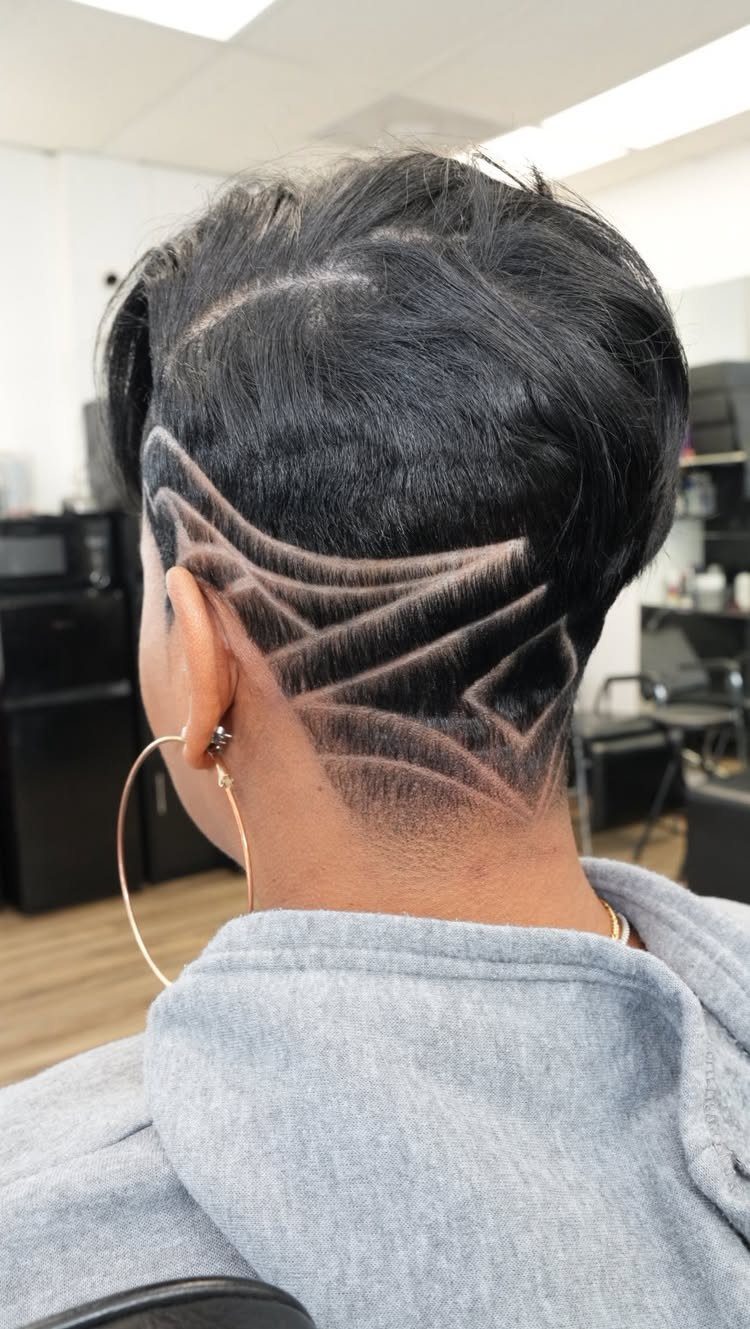 Shaved undercut pixie with curved geometric lines beneath longer black top layers