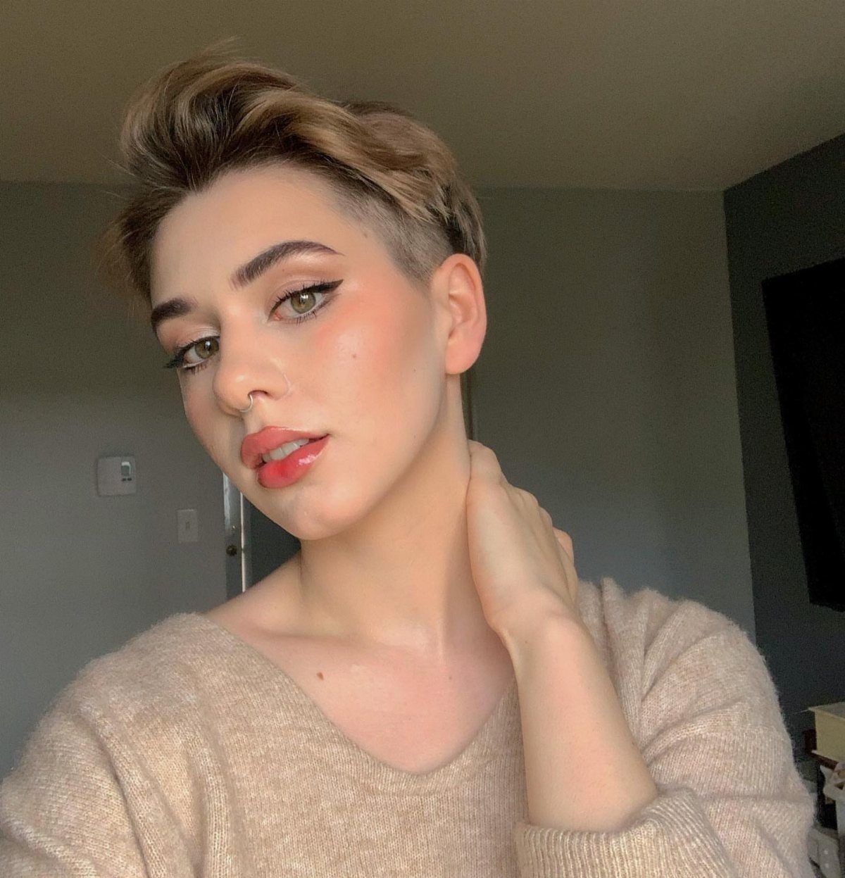 Person showing a brown undercut pixie with longer swept-up top layers