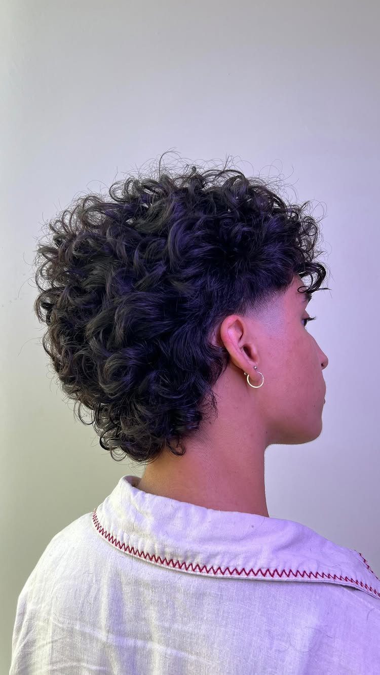 Curly mullet with short sides and longer textured curls at the nape