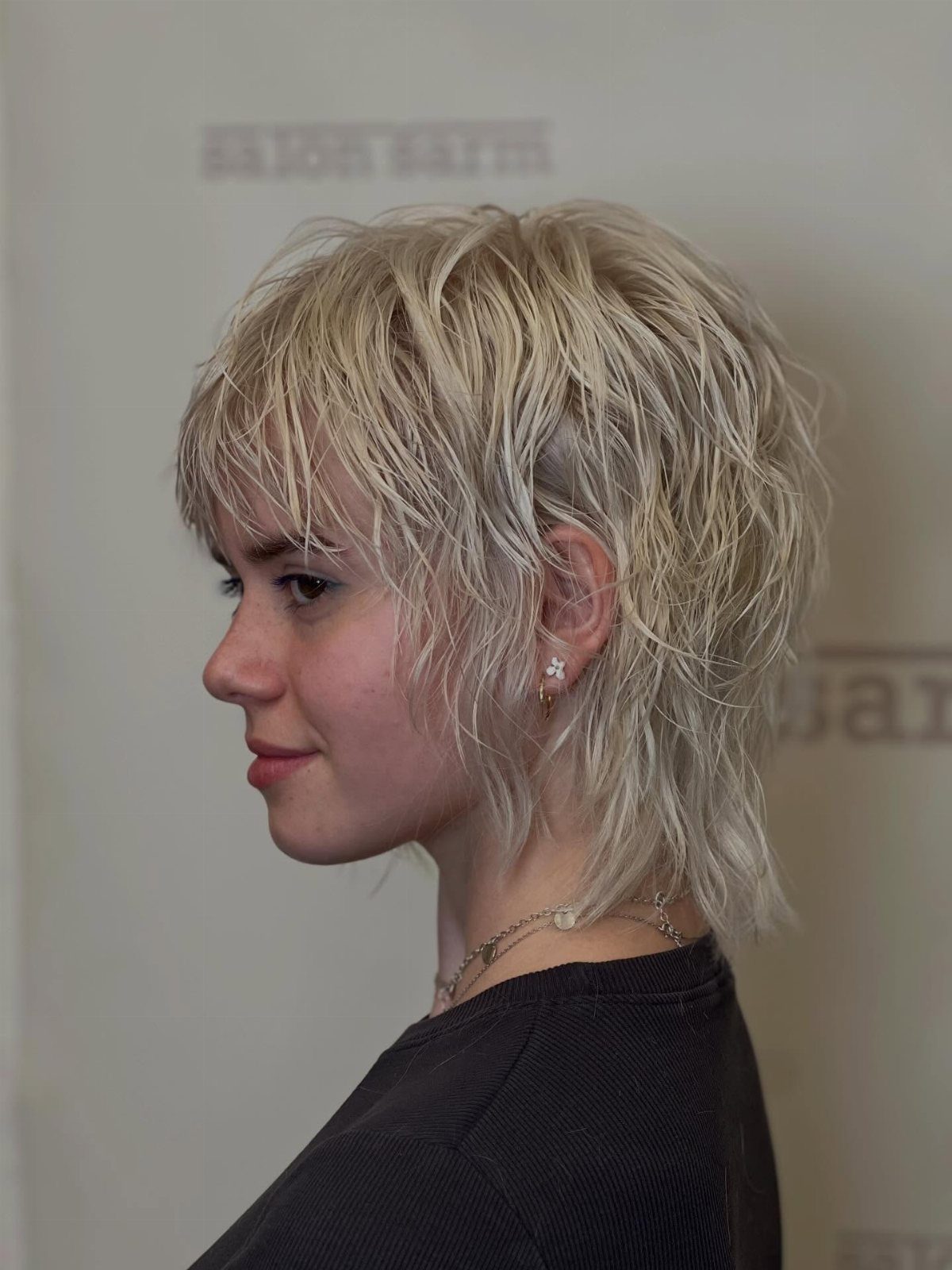 Blond-haired person showing a wispy, layered shag haircut in side profile