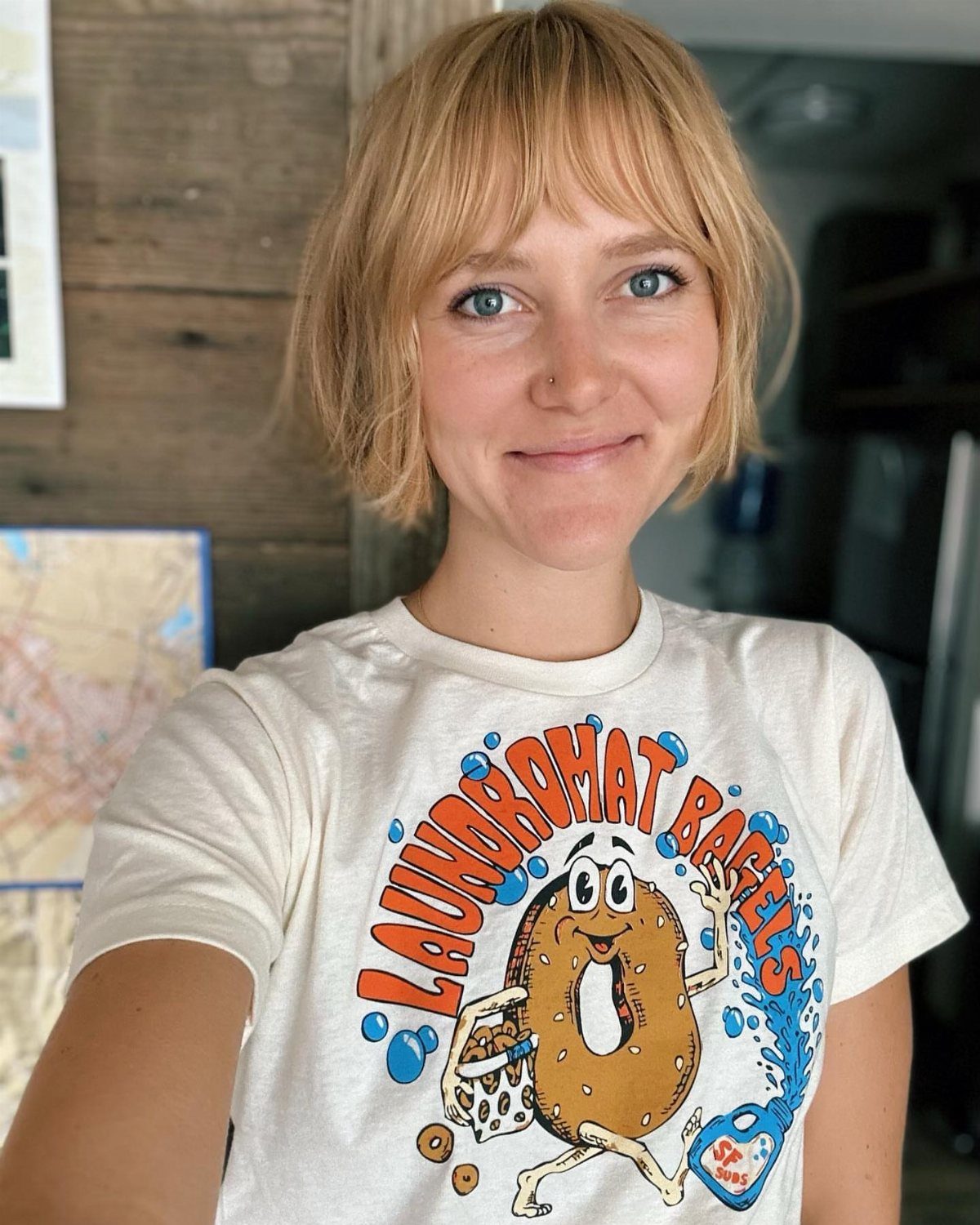 Woman with a short blonde bob and wispy bangs wearing a graphic T-shirt