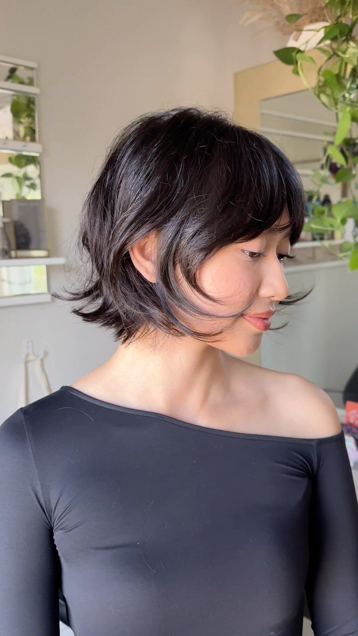 Woman showing a textured dark bixie haircut with wispy bangs