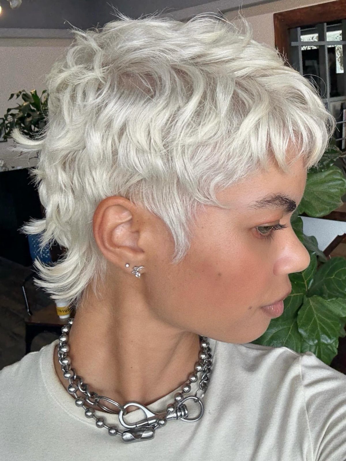 Platinum-haired person showing a tousled, wispy layered pixie cut