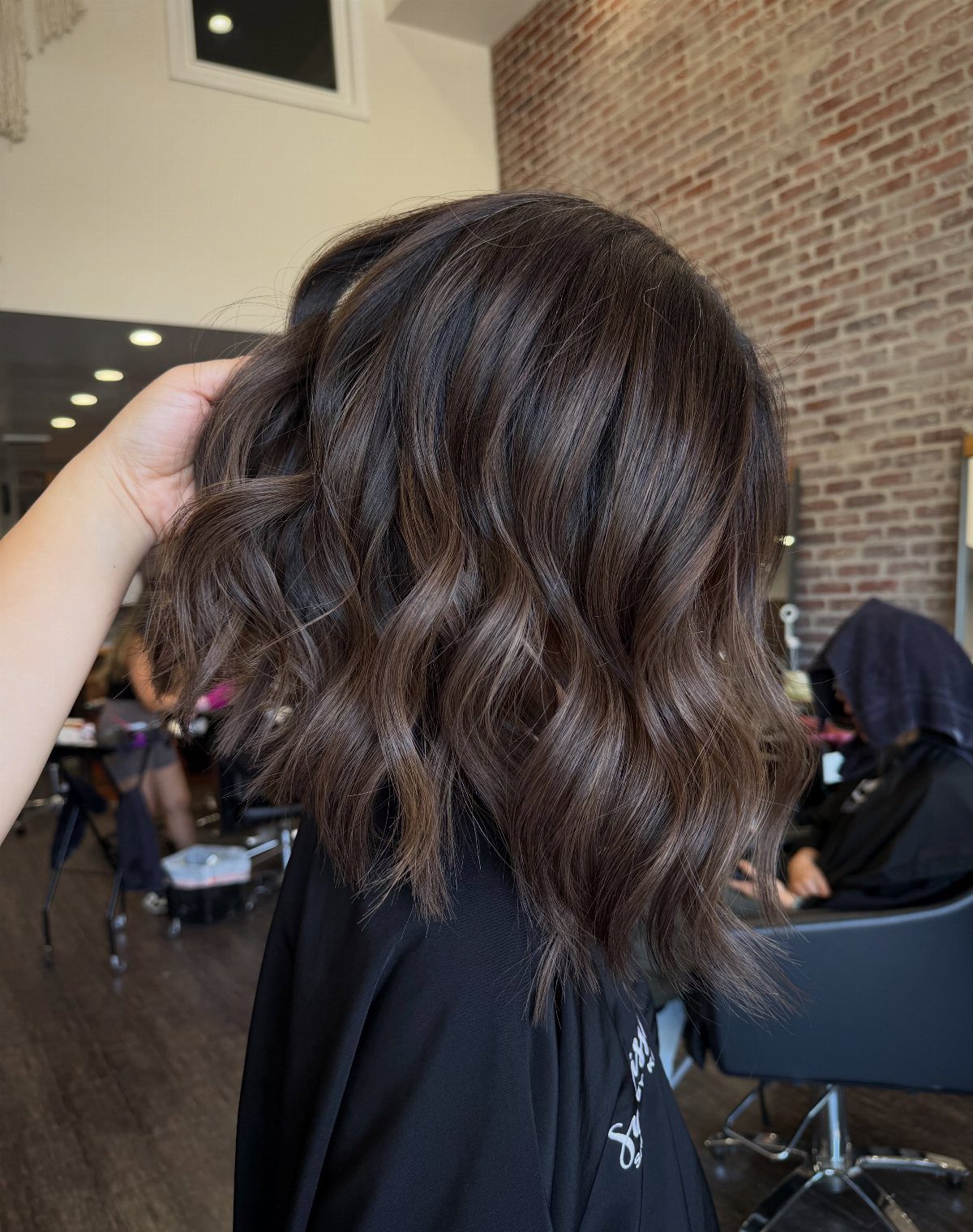 Shoulder-length dark hair with loose piecey waves and subtle highlights in a salon