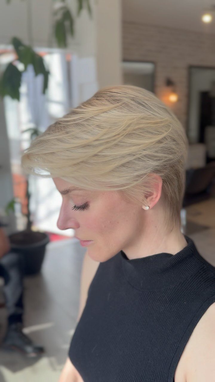 Woman with a long feathered blonde pixie haircut swept across her forehead