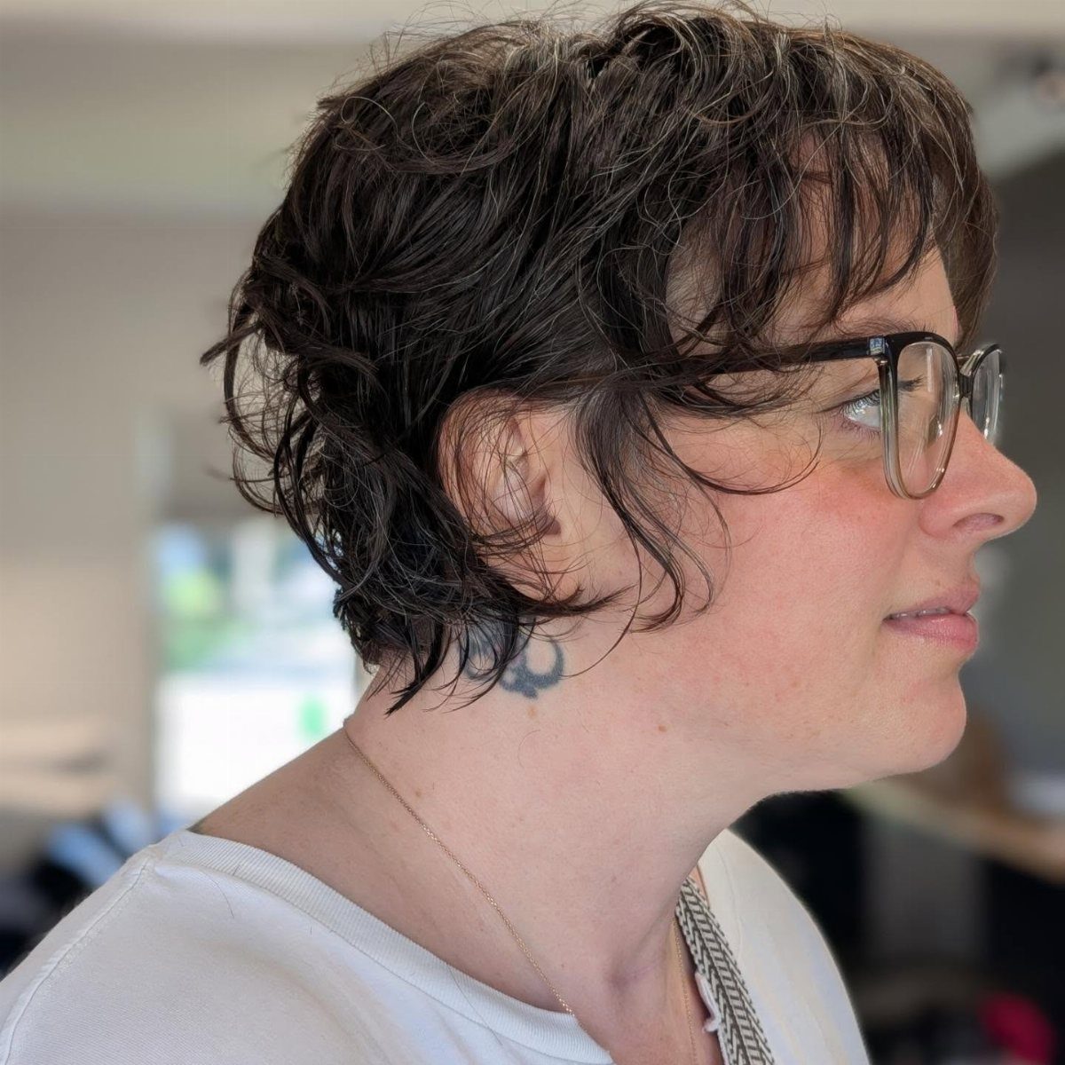 Person with messy short dark pixie cut and glasses in profile