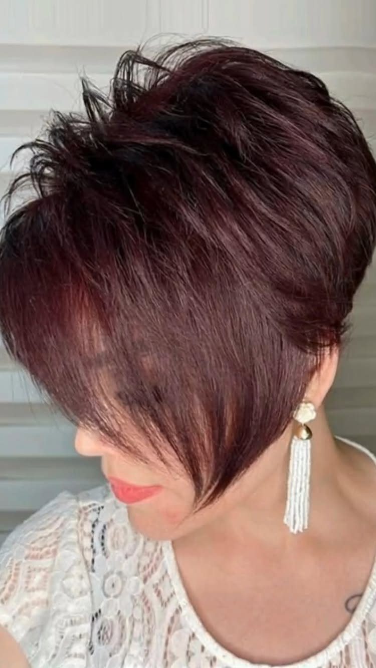 Woman with a messy burgundy pixie haircut and long side-swept bangs