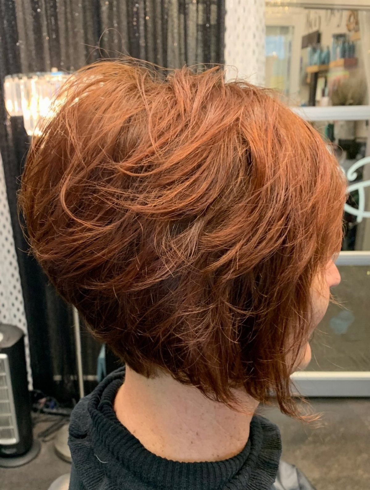 Layered copper-red stacked bob tapered at the nape in a salon
