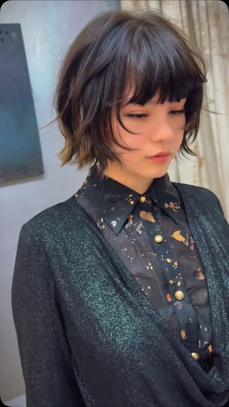 Person with a softly stacked dark bixie, layered sides, and long bangs