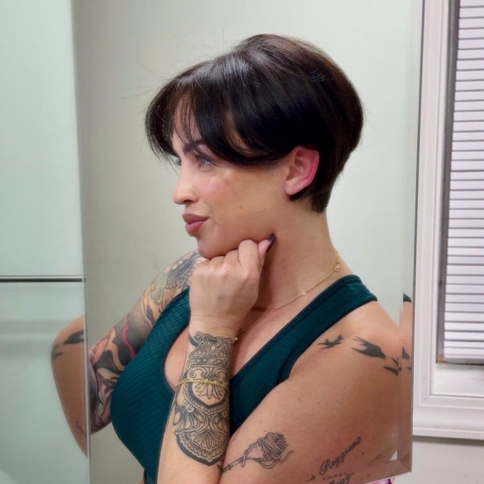 Person models a tapered dark pixie haircut with long side-swept bangs