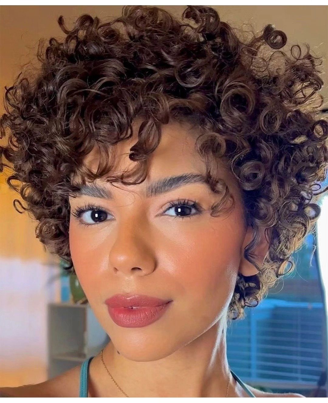 Person with tousled short dark curls styled in a pixie cut