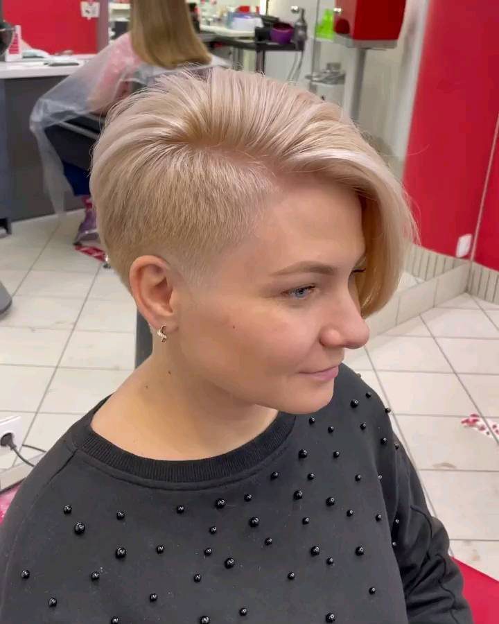 Blonde asymmetrical pixie cut with a long swept top and closely cropped sides
