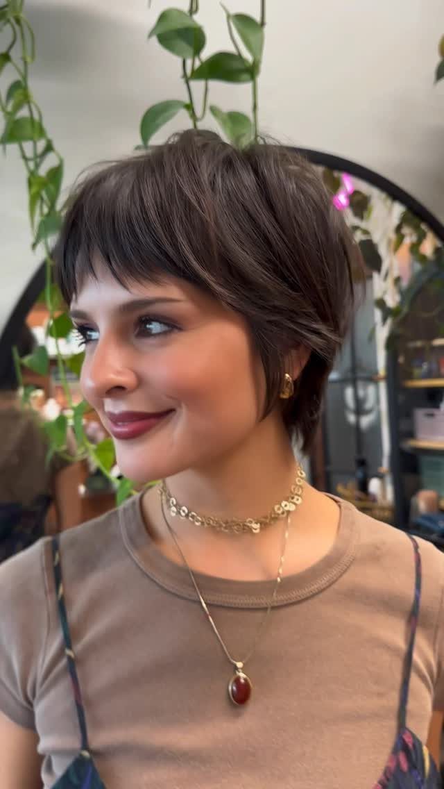 Woman wearing a dark pixie cut with short front fringe indoors