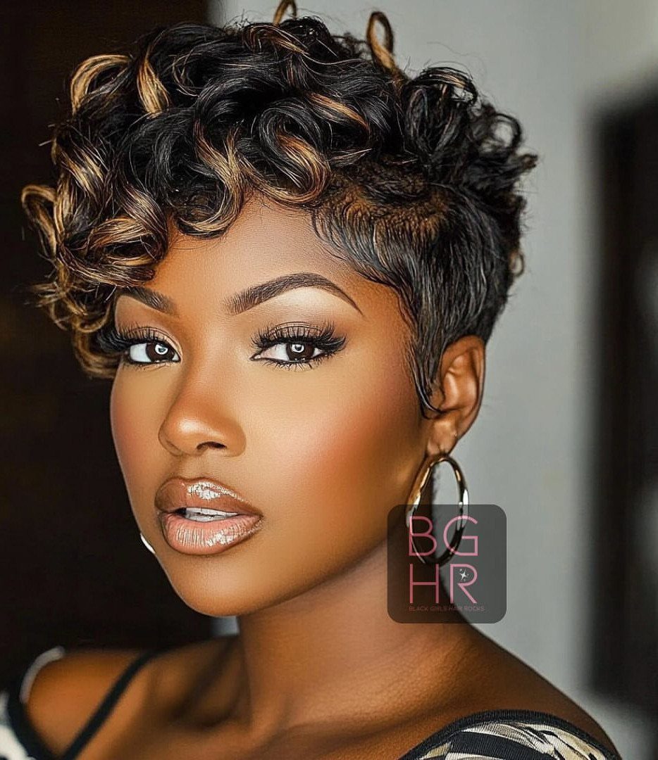 Woman with sculpted short curls and caramel highlights posing in hoop earrings