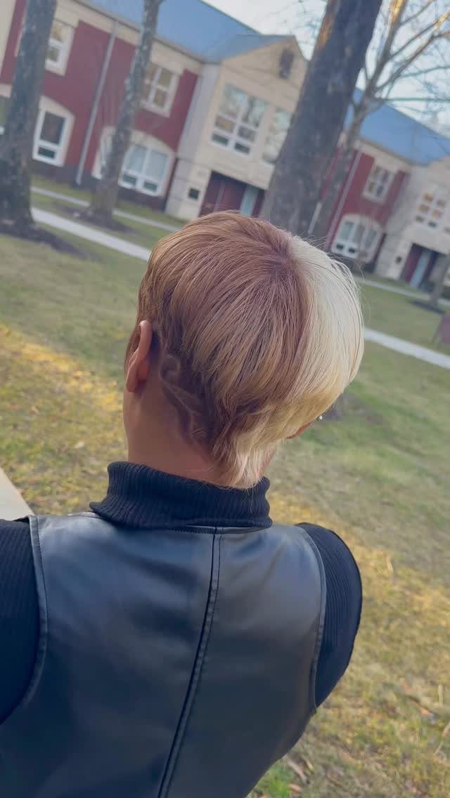 Two-tone pixie haircut with blonde and mauve-brown sections seen from behind
