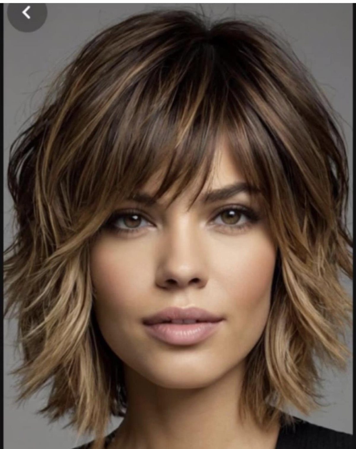Woman with a short brown shag haircut, feathered layers and dramatic fringe