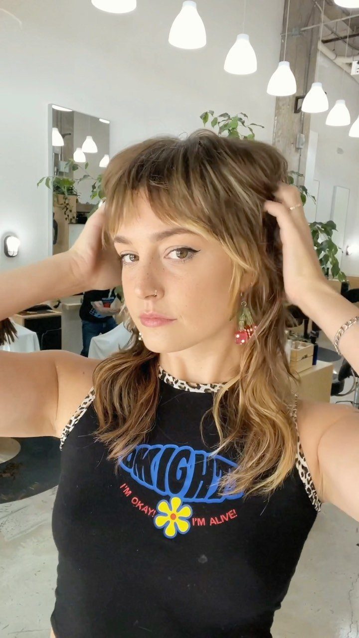 Woman showing a tousled, wavy shag haircut with short fringe in a salon