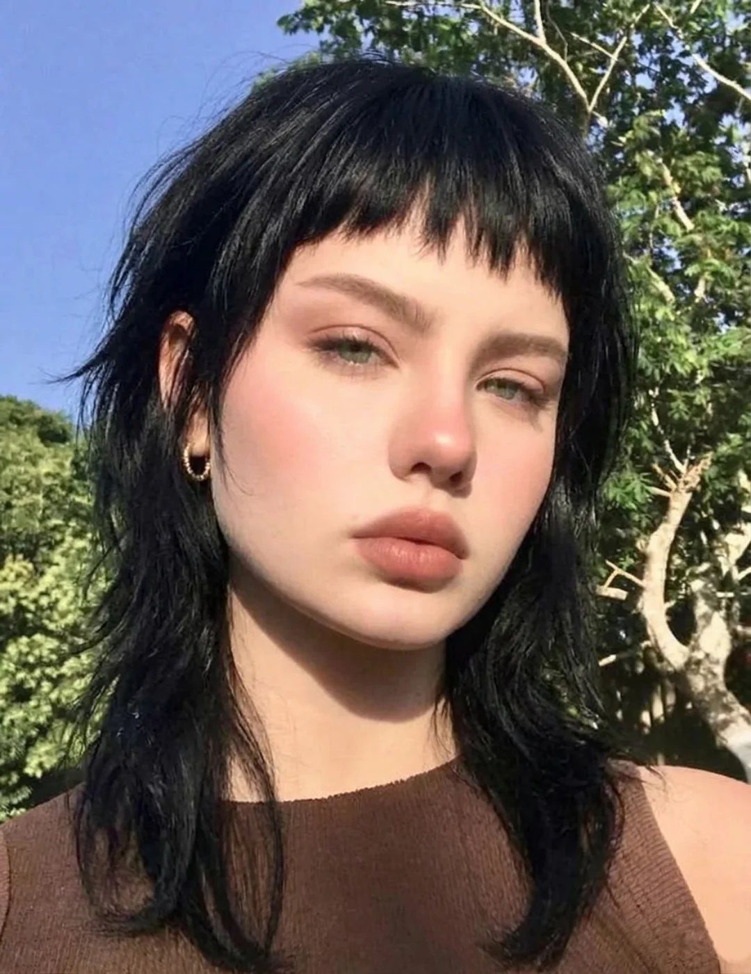 Black choppy layered shag haircut with short uneven bangs outdoors