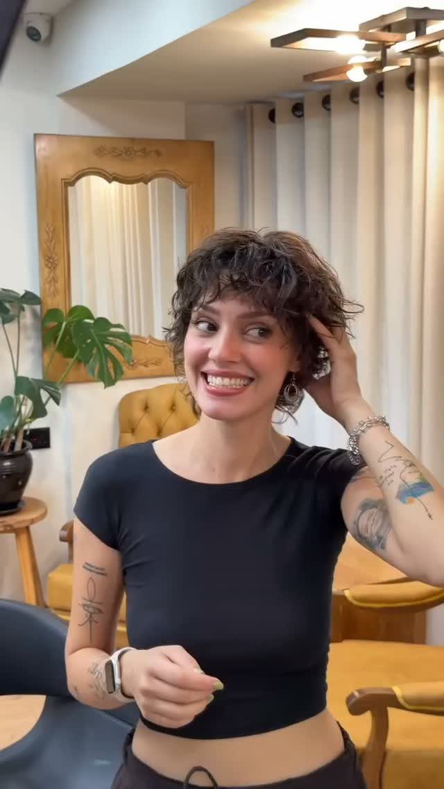 Woman showing a short curly pixie shag with layered fringe in a salon