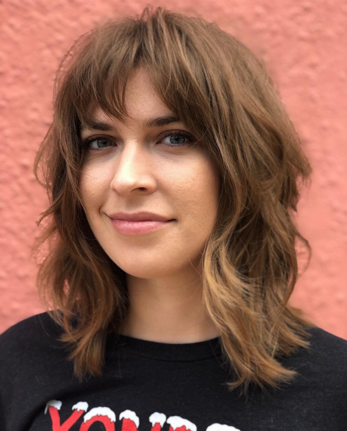 Woman with a short brown wavy shag haircut and wispy fringe