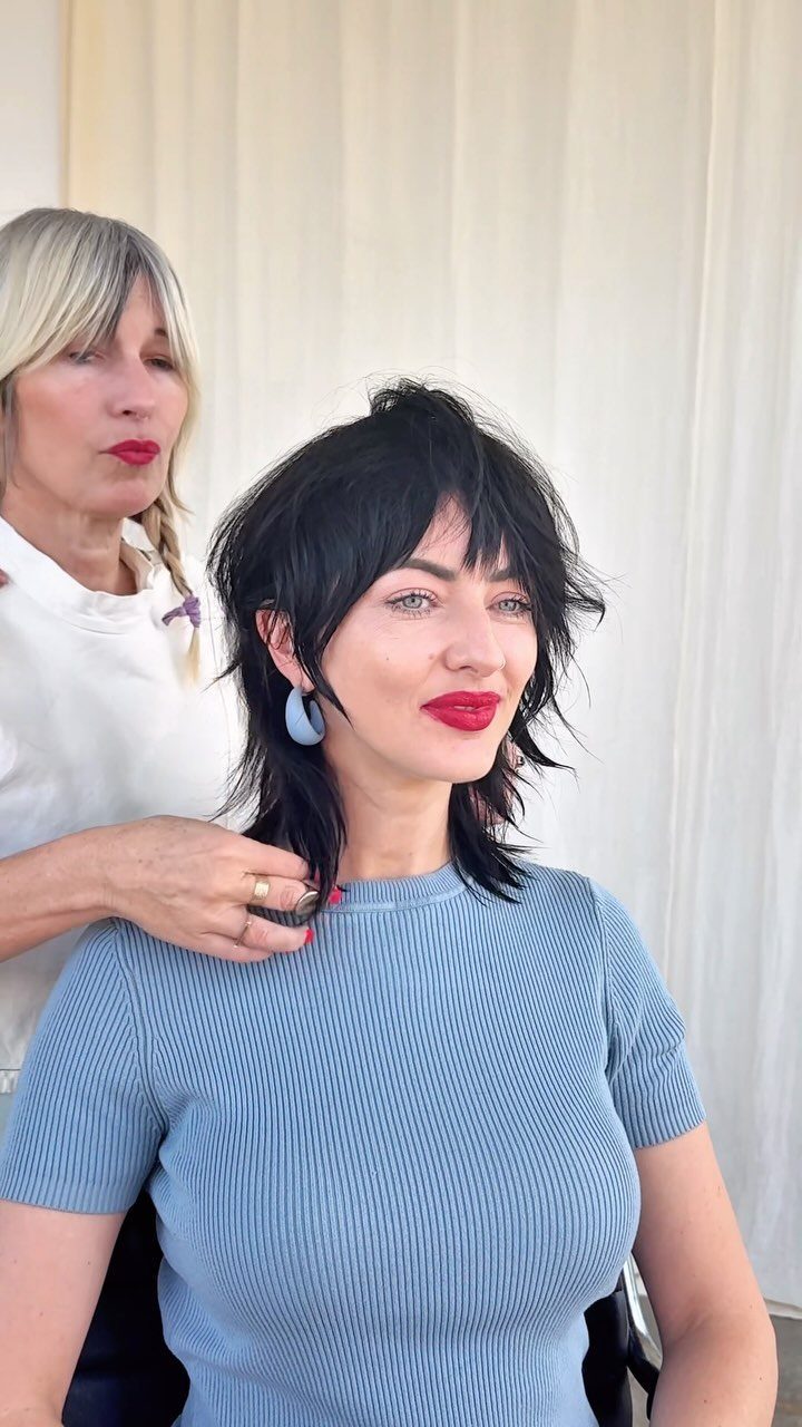 Woman with short dark razor shag haircut and separated jagged layers seated before stylist