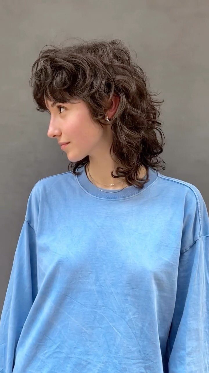 Profile of a person with a short curly shag, crown volume, and face-framing fringe