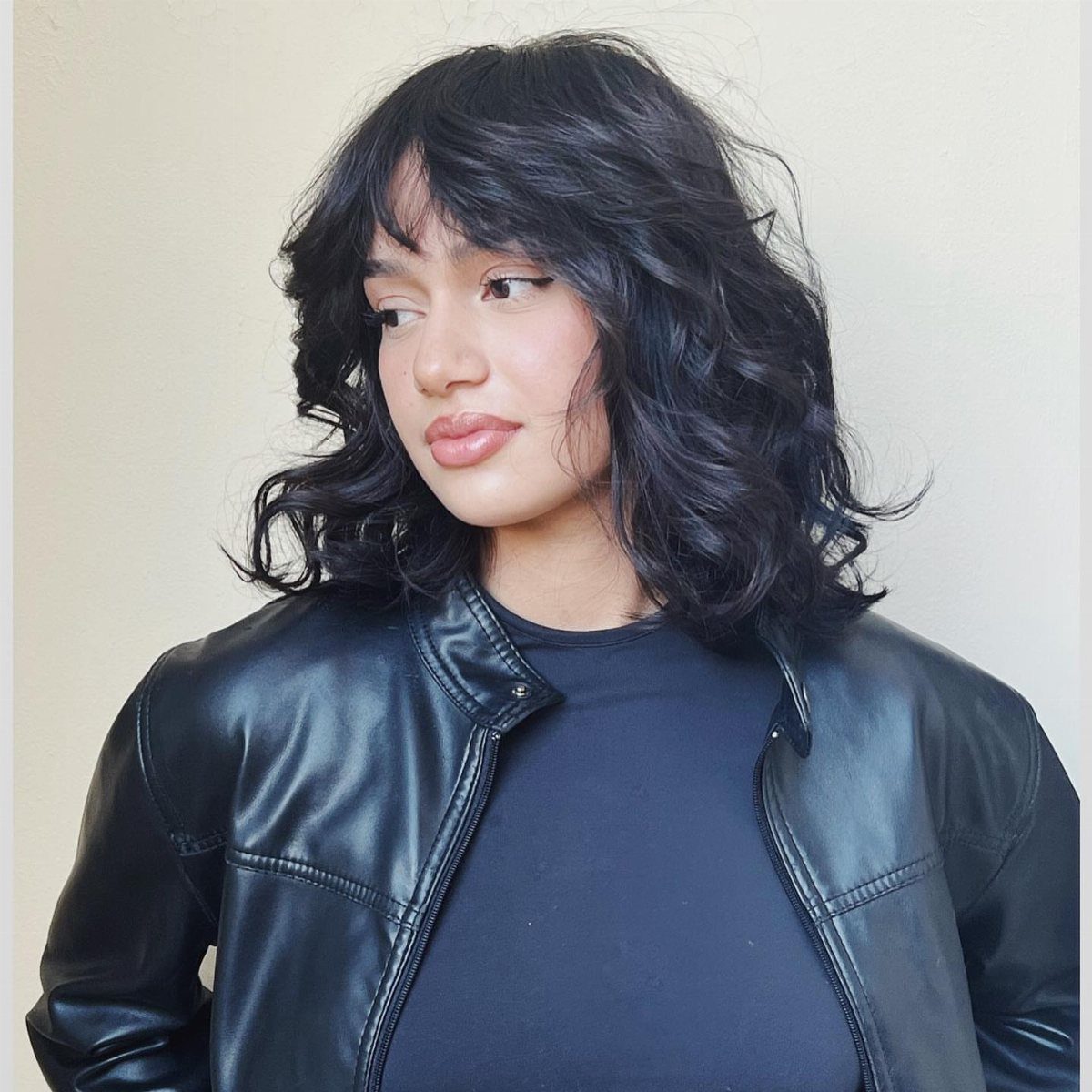 Person with a tousled black short shag haircut and wispy bangs