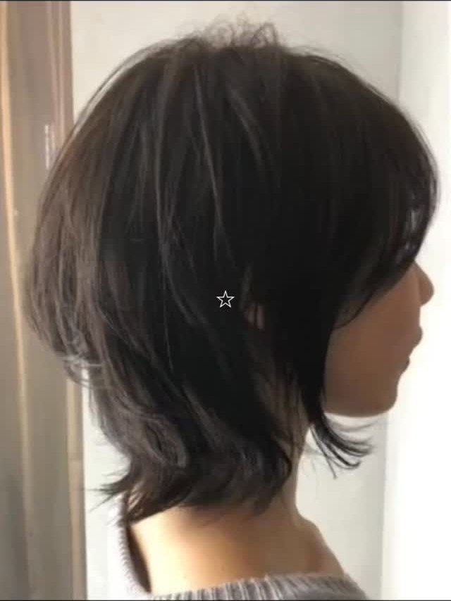 Short dark shag haircut with layered sides, tapered bangs, and flipped-out ends