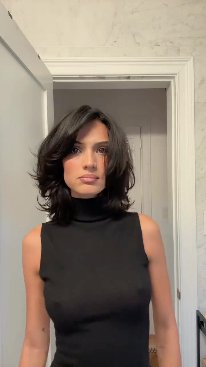 Woman with a short, layered dark shag haircut and side-swept bangs