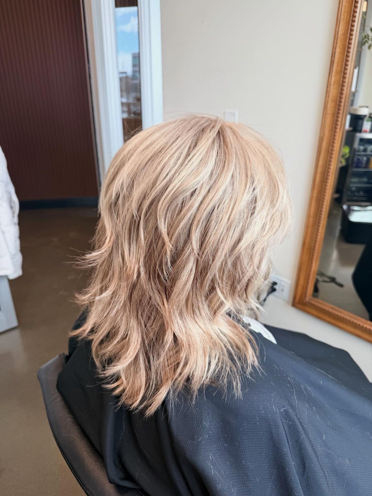 Softly layered blonde shag haircut with feathered ends in a salon