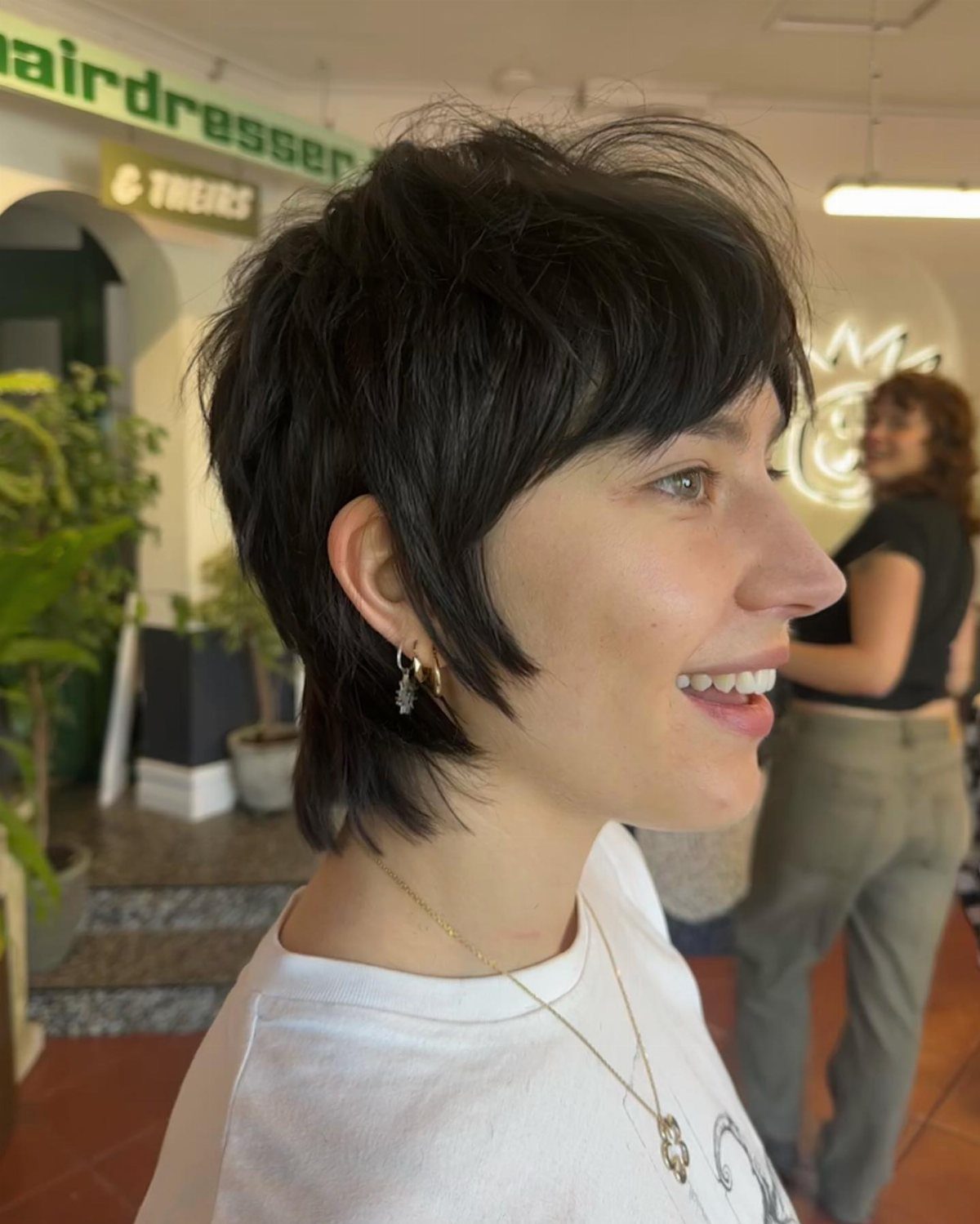 Short dark shag haircut with tousled crown, side-swept bangs, and tapered nape