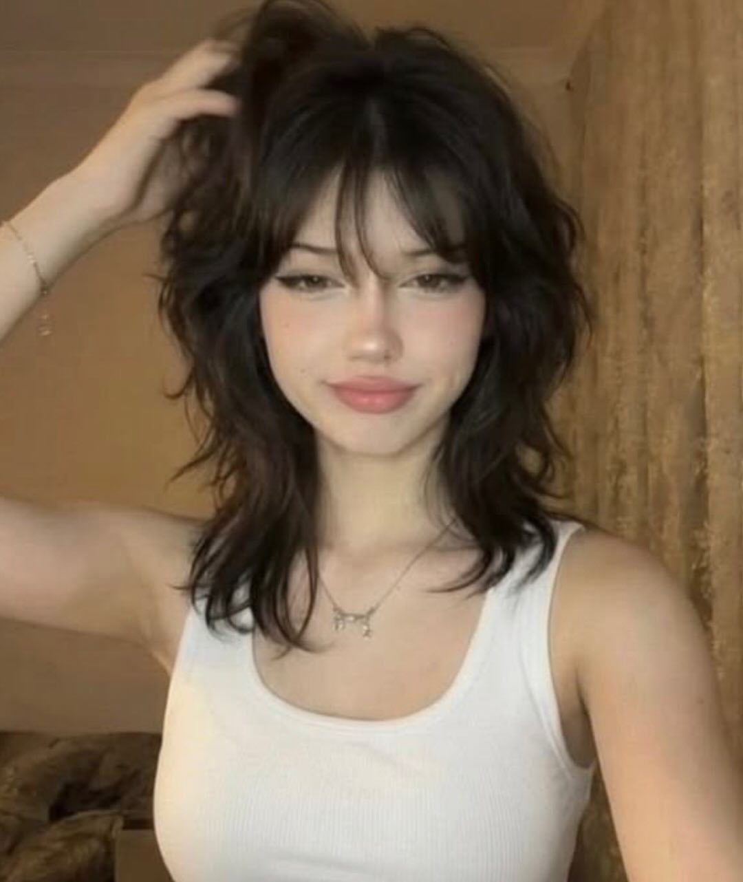 Woman showing a dark wolf cut with choppy layers and wispy bangs
