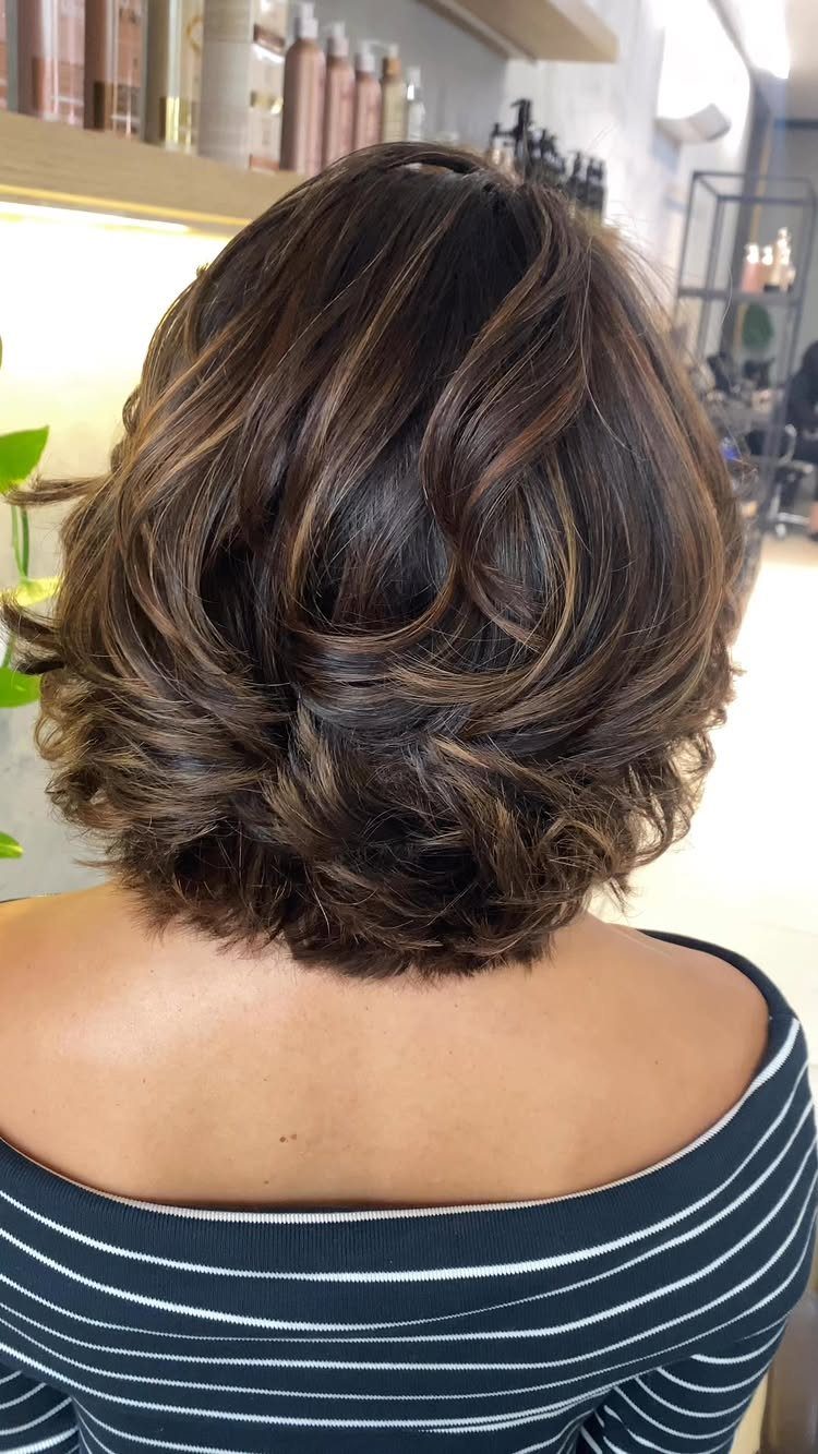 Layered shoulder-length bob with curled ends viewed from behind in a salon