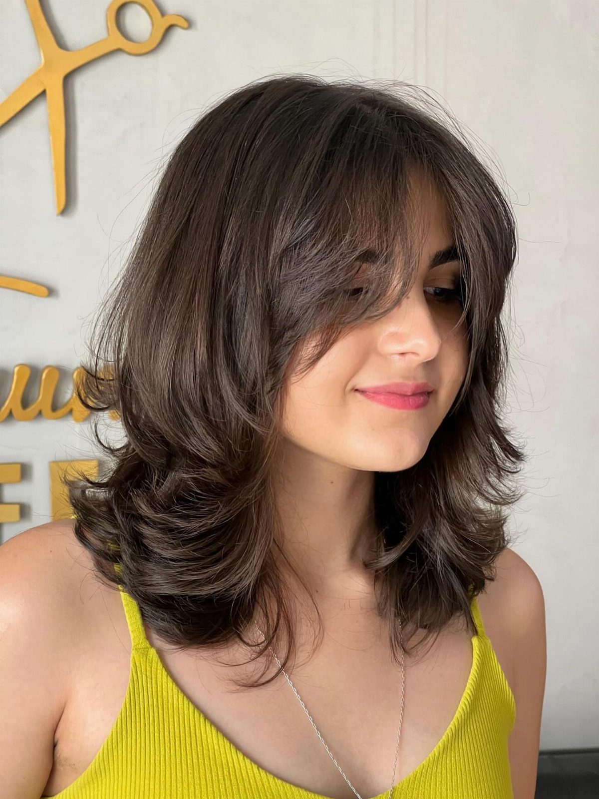 Woman showing a rounded shoulder-length dark brown bob with layered, flipped-out ends