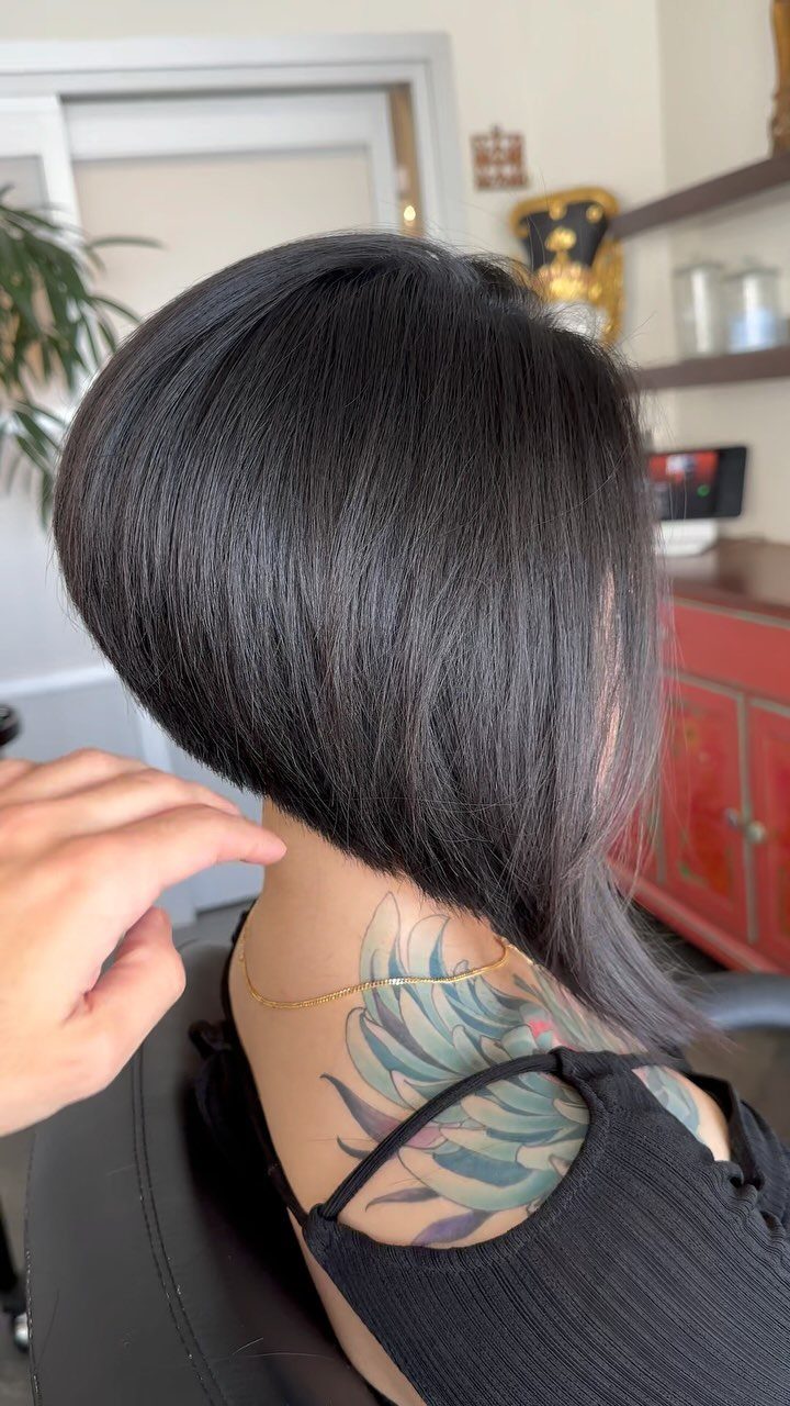 Sleek straight black angled bob haircut viewed from behind in a salon