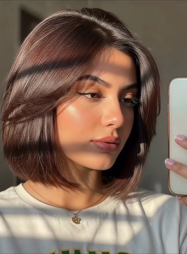 Woman showing a tousled middle-parted medium brown bob in a mirror selfie