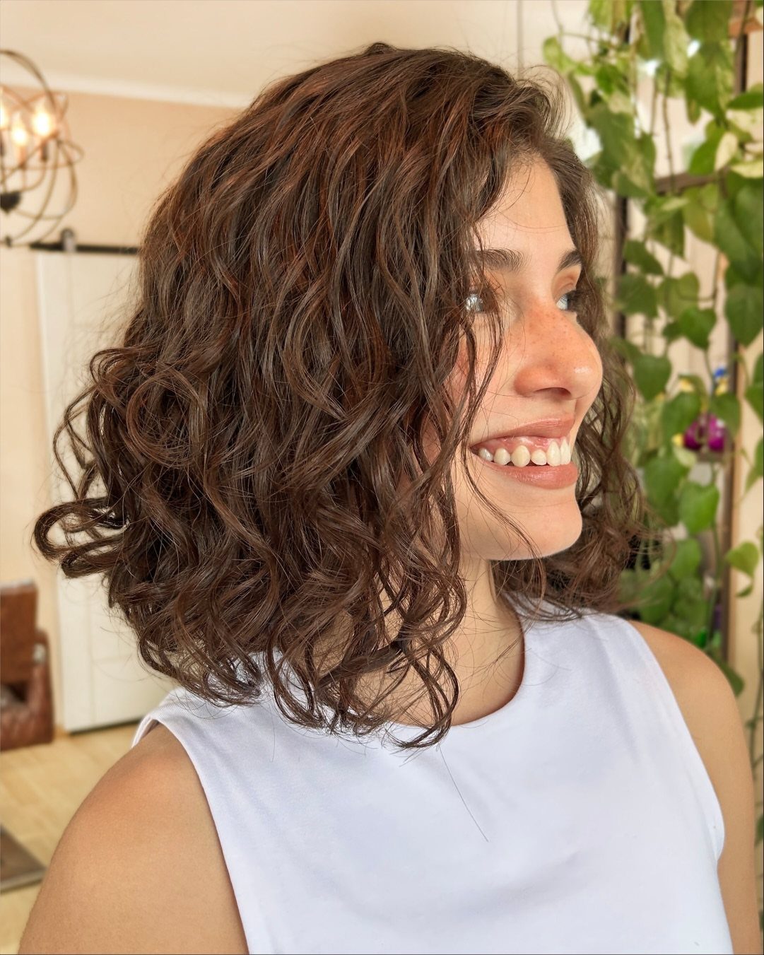 Woman smiling with a shoulder-length dark brown wavy bob hairstyle