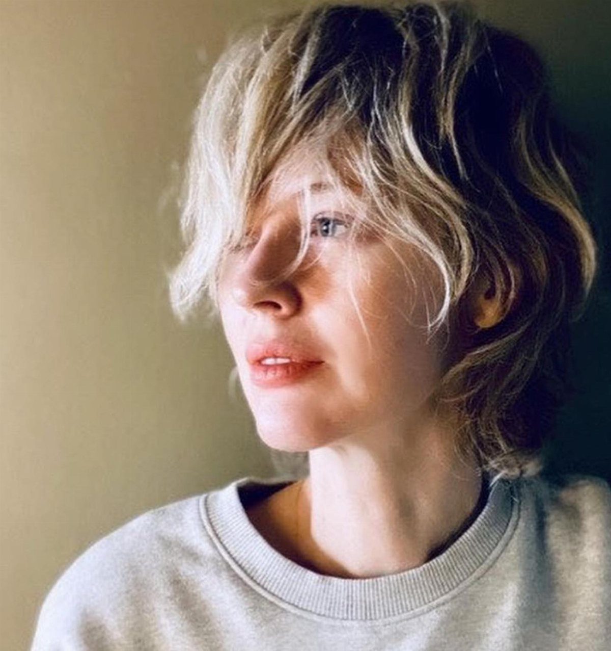 Woman with layered blonde hair and long side-swept bangs across her forehead